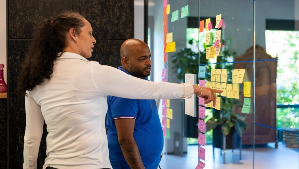 Two people discussing post-its on a glass wall