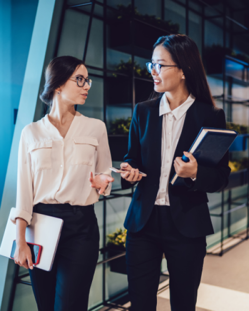 Two professionals walking and talking in an office.